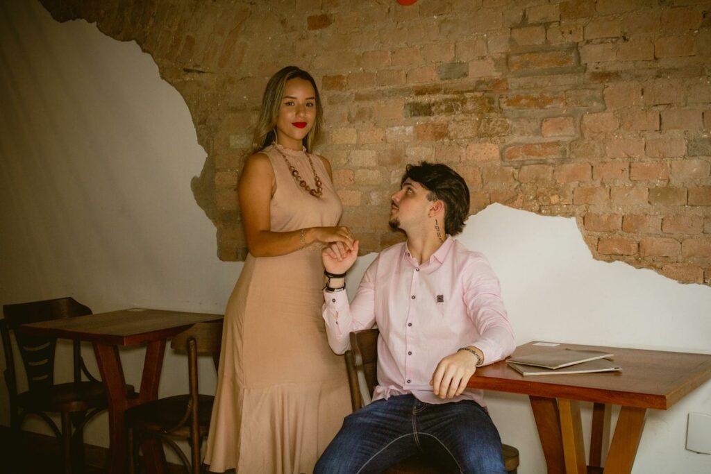 A man and woman sitting at a table in front of a brick wall