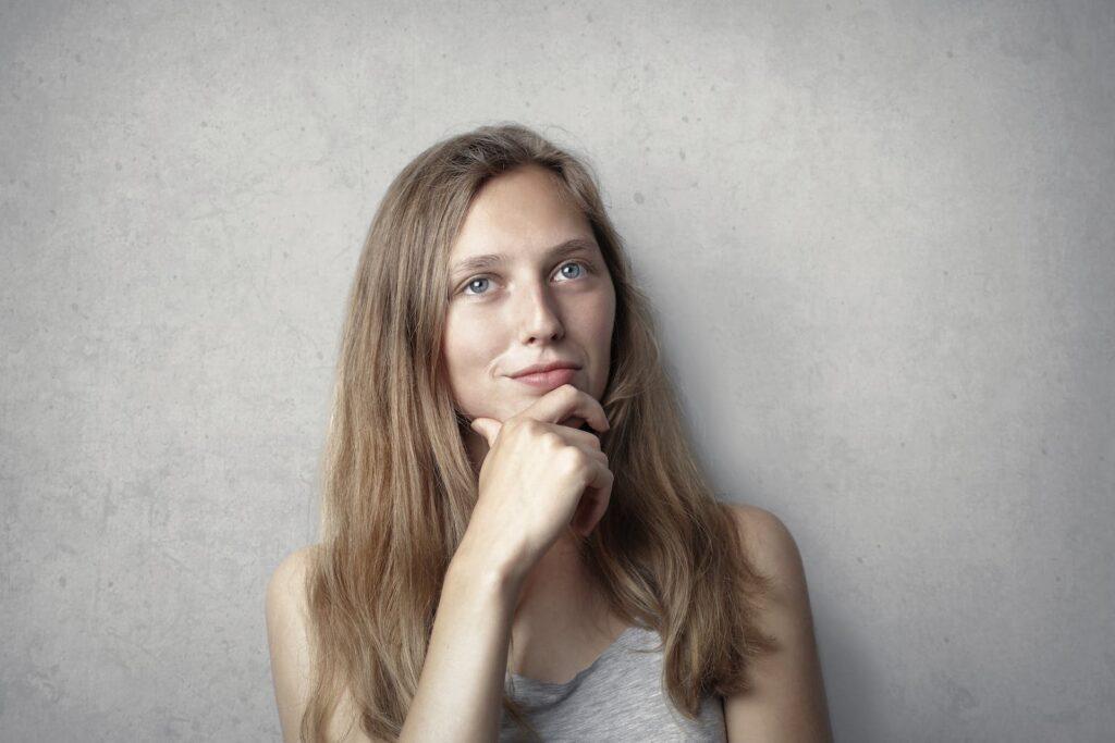 Woman in Gray Tank Top While Holding Her Chin