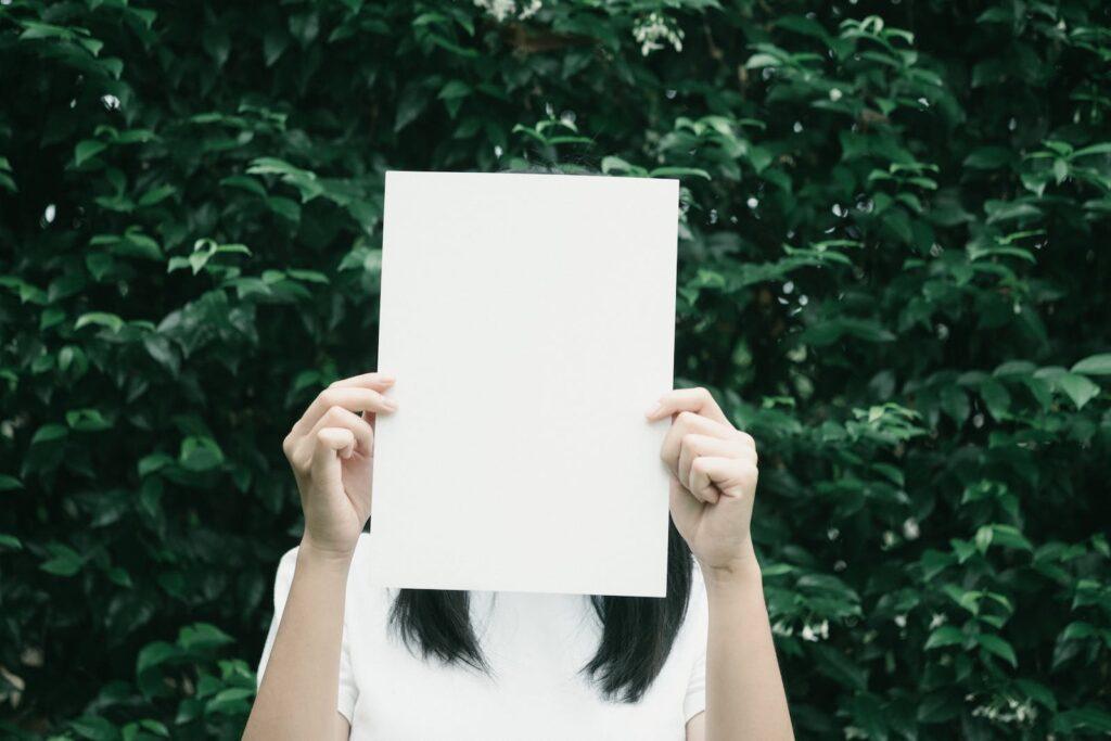 Woman Holding White Printer Paper Beside Leaf Plant