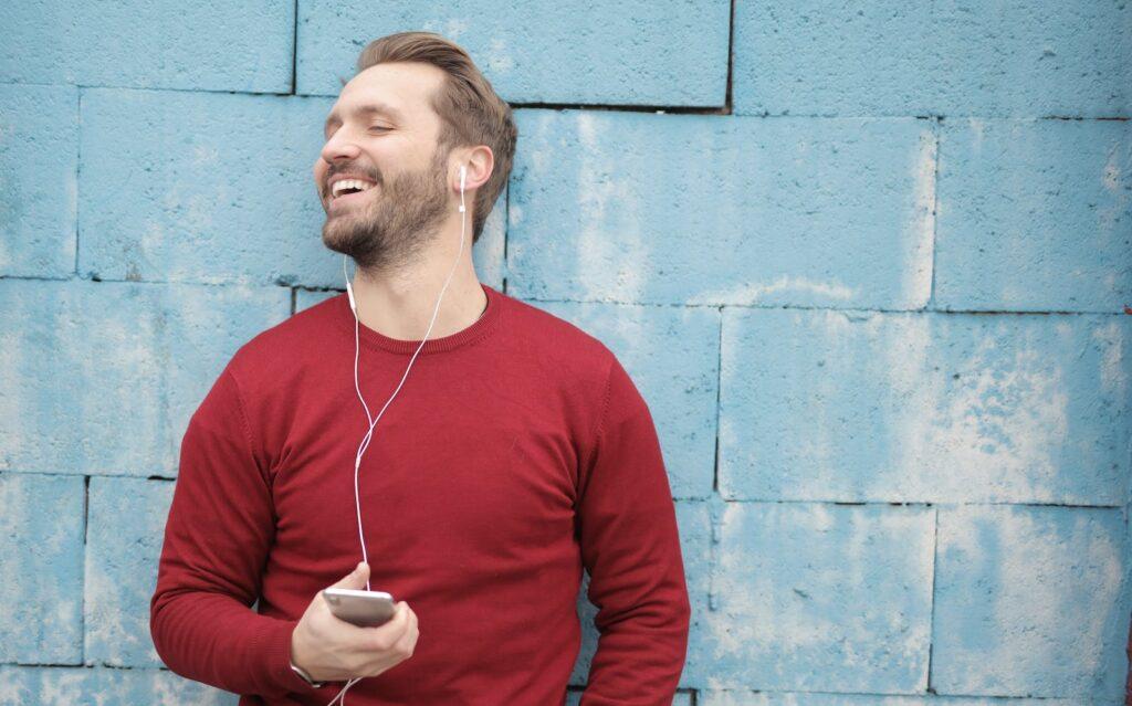 Man in Red Long Sleeve Shirt Wearing White Earbuds