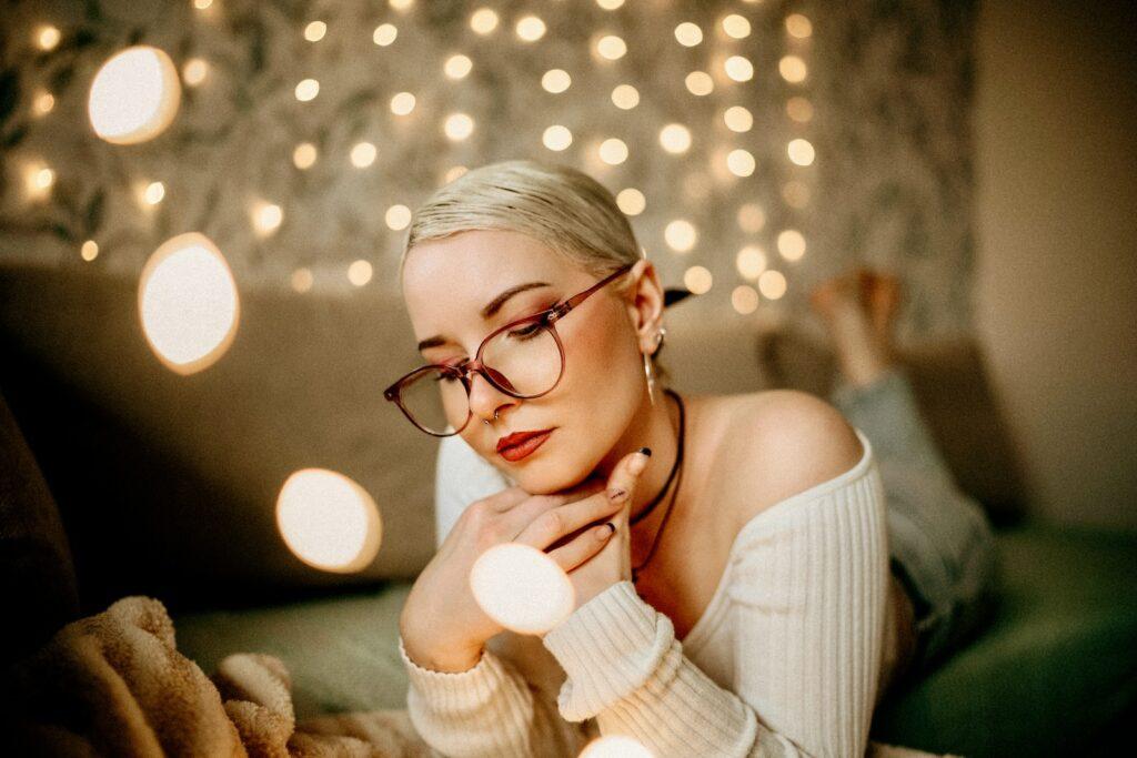 a woman wearing glasses laying on a couch