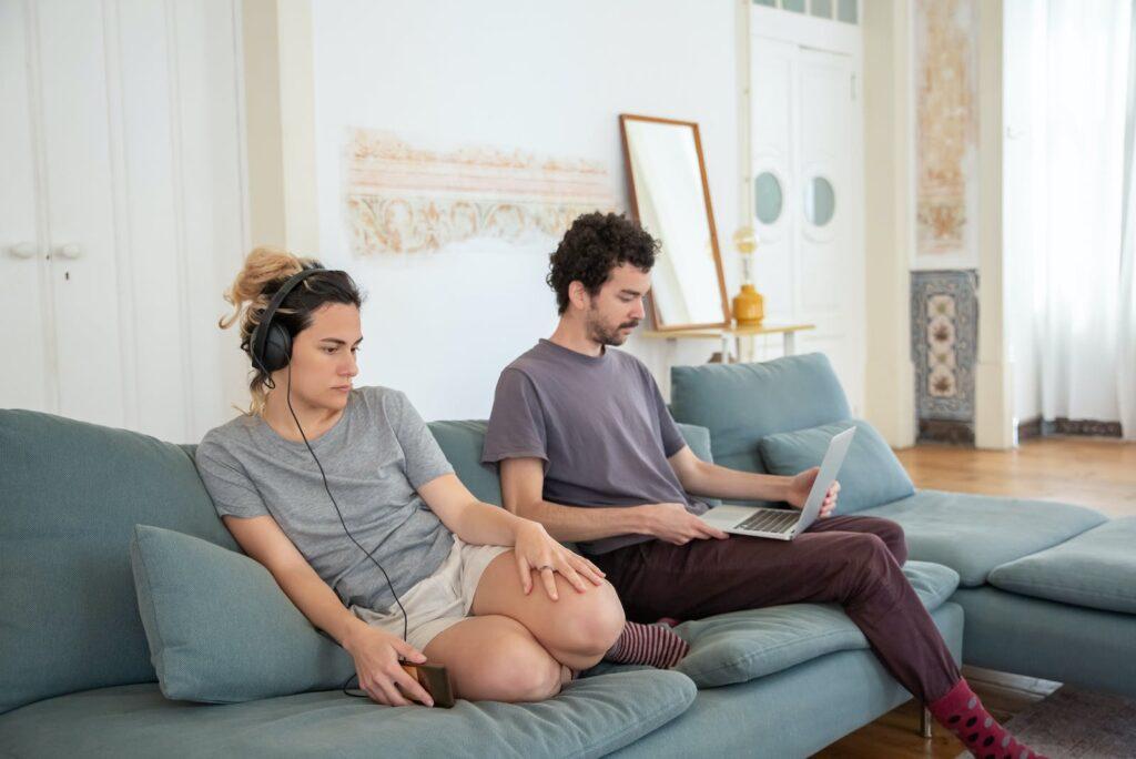 Woman with Headphones Sitting Next to Man with Laptop