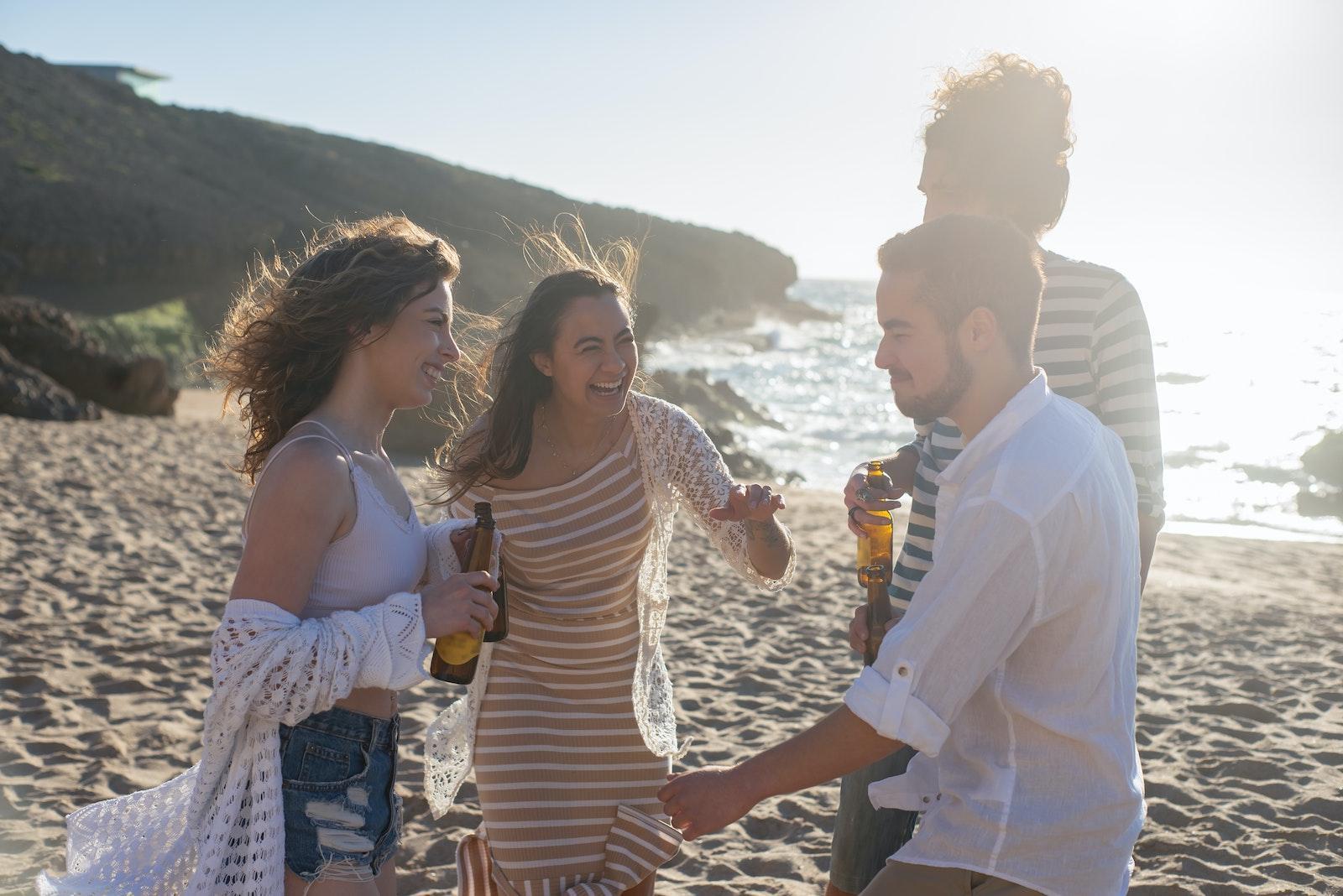 People Standing on Beach Sand while Drinking Beer