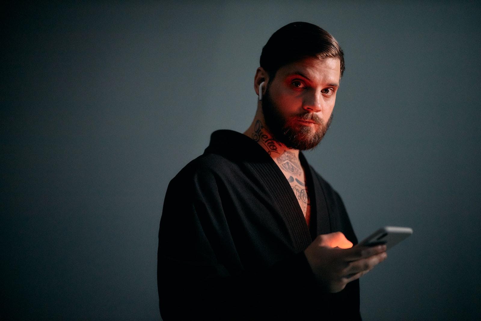 Close Up Photo of Man in Black Suit Holding Smartphone