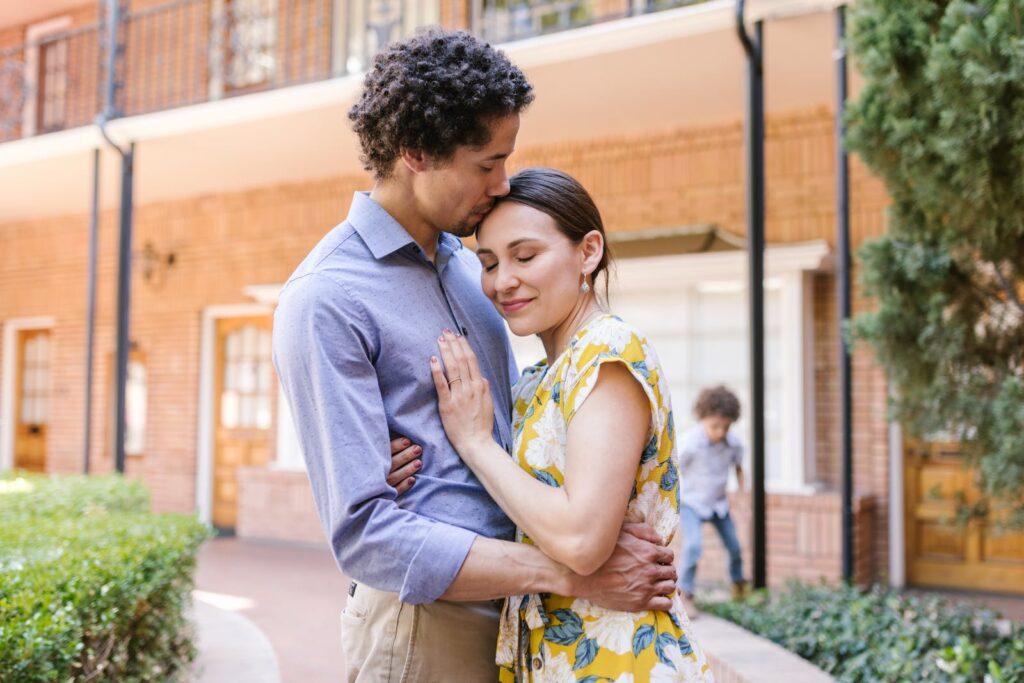 Couple Hugging and Their Son Running in the Background