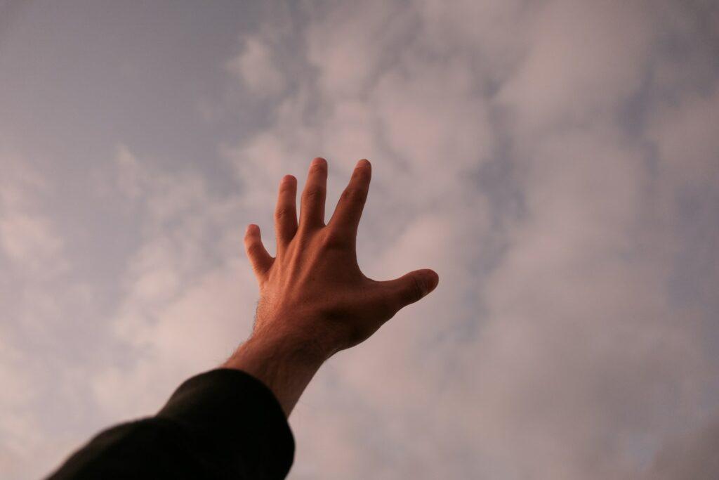 a person's hand reaching up into the sky