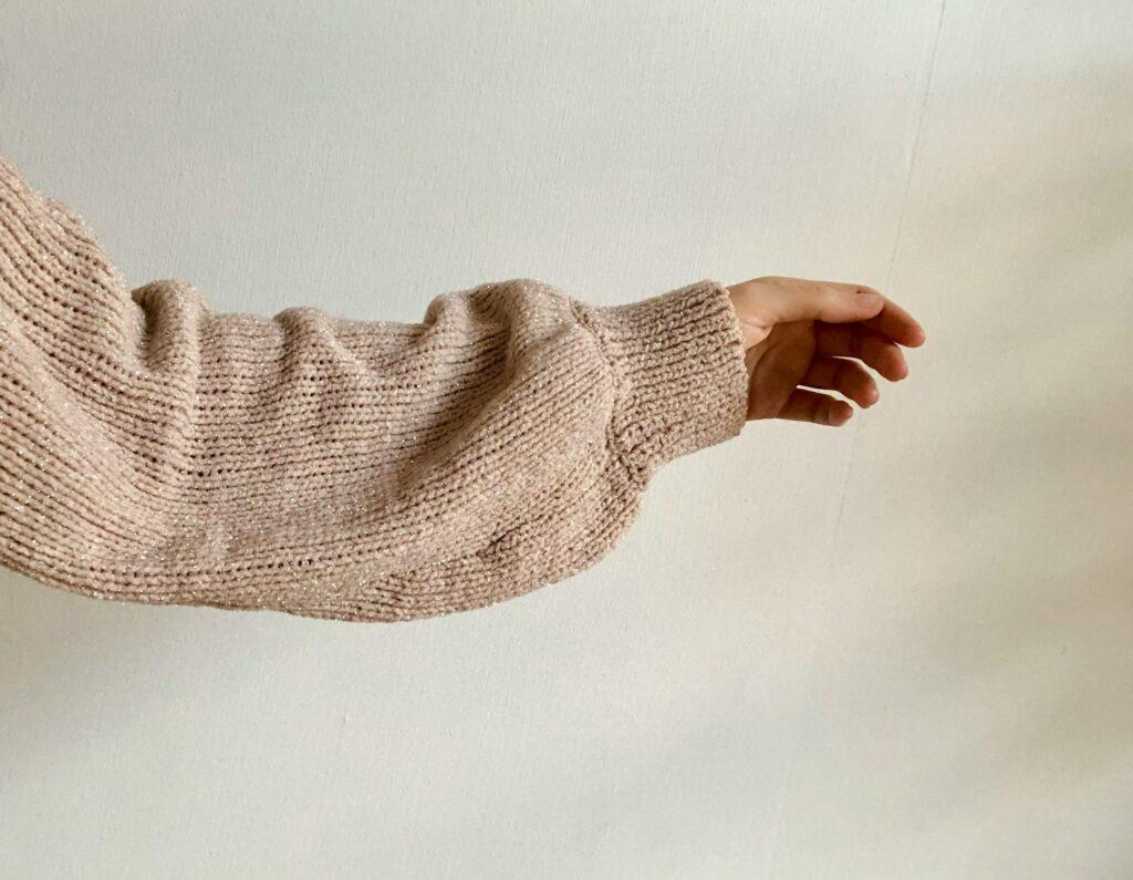 a person's arm with a knitted sweater on