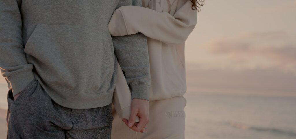 a man and a woman holding hands by the ocean