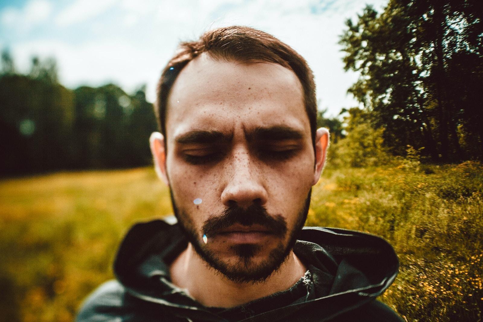 a man with a cigarette in his mouth standing in a field