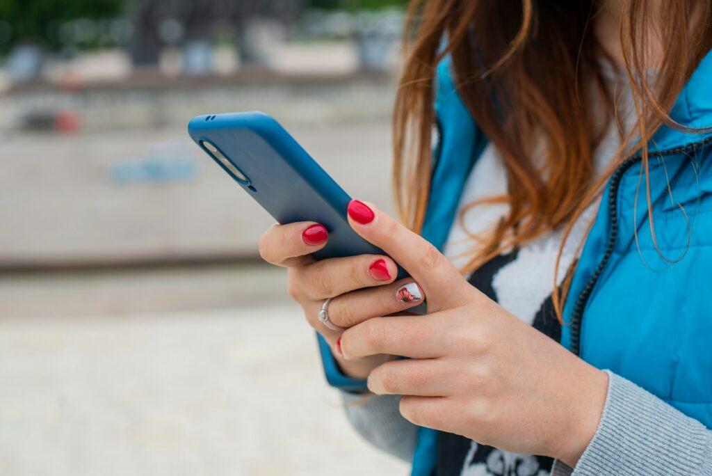 girl writes sms text in the device phone in her hands