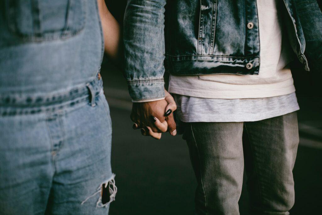 two person holding hands while walking