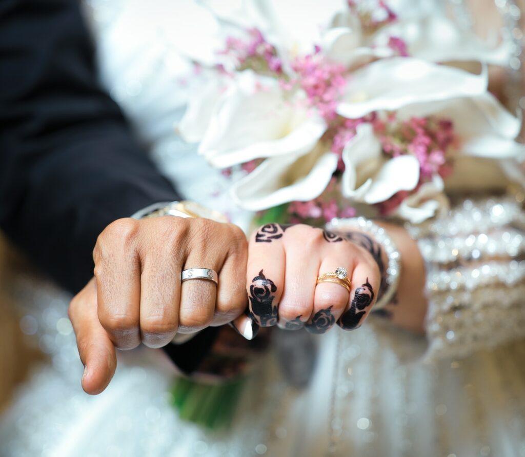 a bride and groom holding hands with their wedding rings