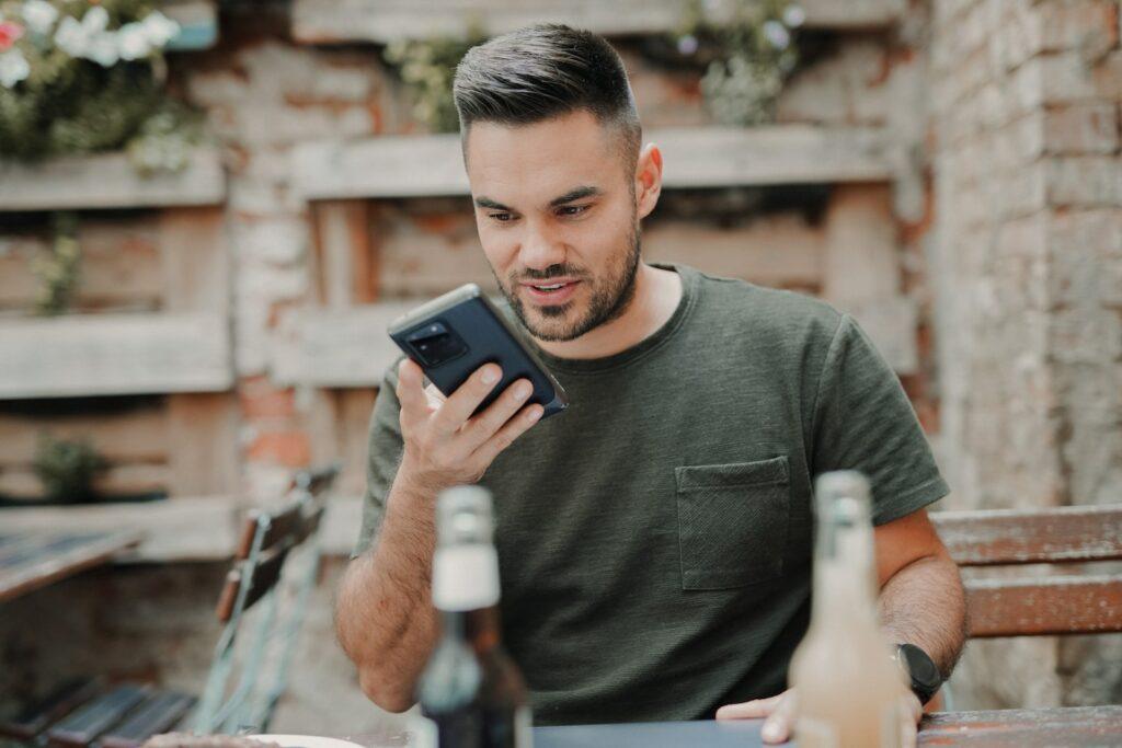 man in gray crew neck long sleeve shirt holding black smartphone