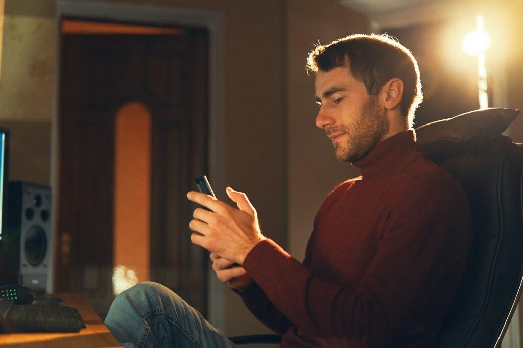 Young man working in the studio using a smartphone and computer.
